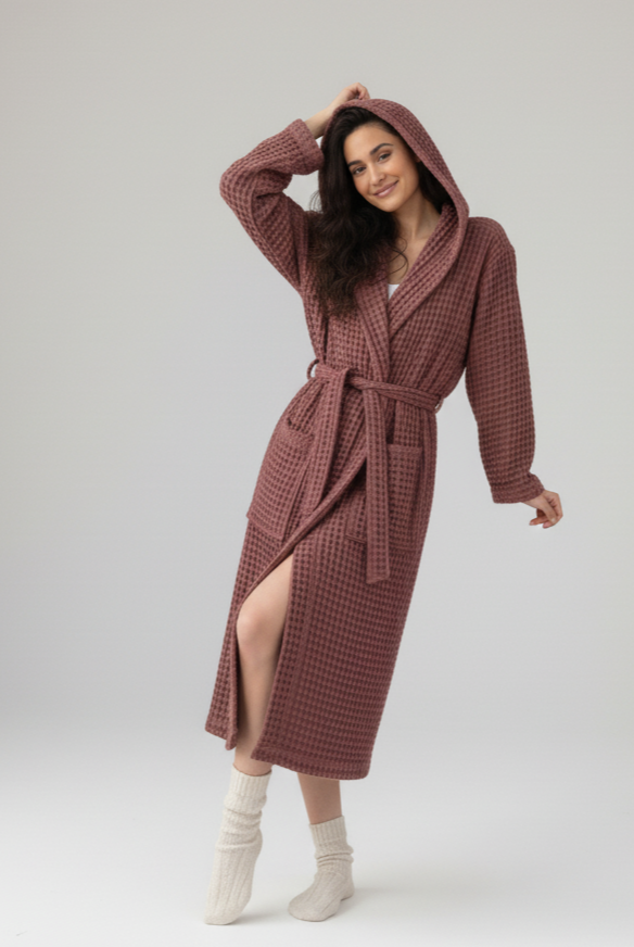 Woman wearing a hooded waffle robe on a white background