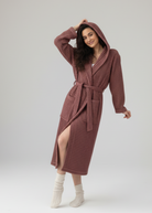 Woman wearing a hooded waffle robe on a white background