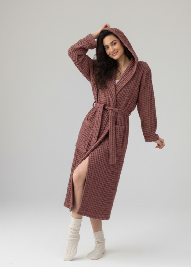 Woman wearing a hooded waffle robe on a white background
