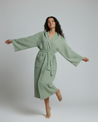 Woman wearing a light green robe against a plain background