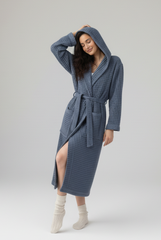 Woman wearing a blue hooded cotton waffle robe on a white background
