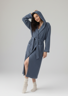 Woman wearing a blue hooded cotton waffle robe on a white background