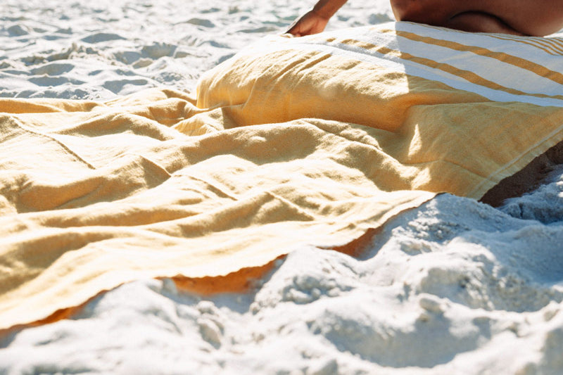woman holding a yellow turkish towel at the beach